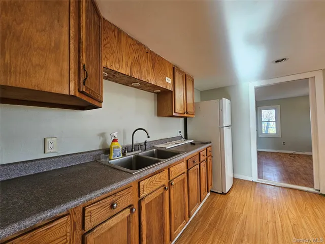 a kitchen with stainless steel appliances granite countertop a sink dishwasher a refrigerator and cabinets with wooden floor