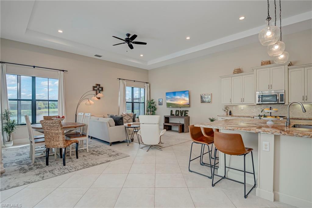 5344 Allen Place Ave Maria, FL 34142 - Photo 10 of 43 Family / Informal Dining Area and Kitchen featuring light stone countertops, decorative light fixtures, decorative backsplash, white cabinets, and ceiling fan