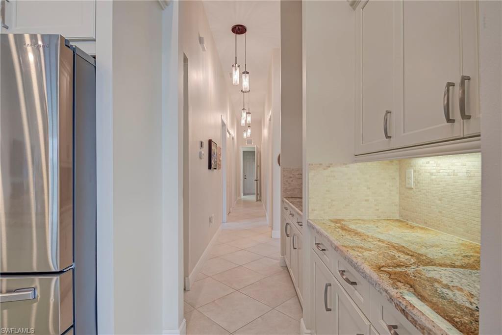 5344 Allen Place Ave Maria, FL 34142 - Photo 14 of 43 Kitchen with freestanding refrigerator, additional cabinetry, light stone countertops, pendant lighting, light tile patterned floors, and decorative backsplash