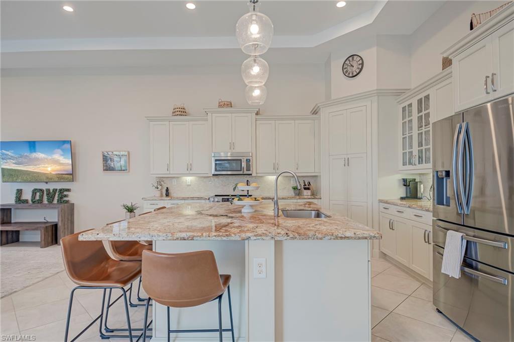 5344 Allen Place Ave Maria, FL 34142 - Photo 8 of 43 Kitchen with stainless steel appliances, pendant lighting, light stone countertops, white cabinetry, and a breakfast bar area