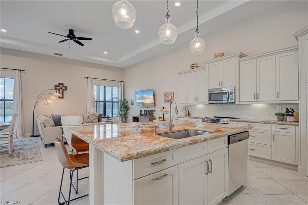 5344 Allen Place Ave Maria, FL 34142 - Photo 42 of 43 Kitchen with white cabinets, open floor plan, light stone counters, an island with sink, and light tile patterned floors
