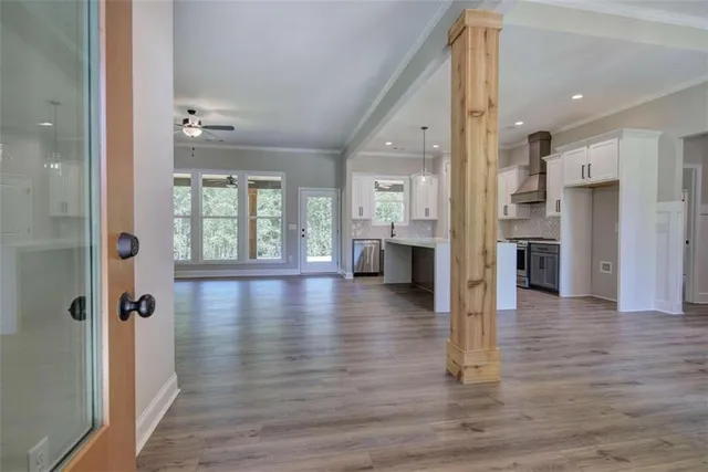a view of a hallway with wooden floor windows and a living room