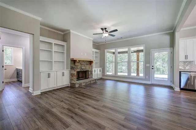 an empty room with wooden floor fireplace and windows