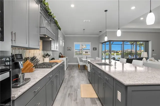 a kitchen with stainless steel appliances granite countertop a sink a counter space and living room view