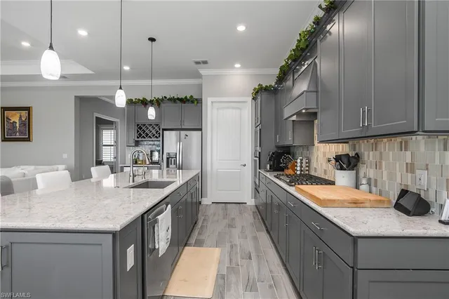 a kitchen with granite countertop kitchen island stainless steel appliances a sink stove and cabinets