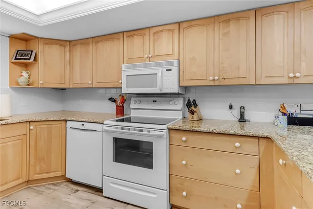 a kitchen with granite countertop white cabinets and white appliances