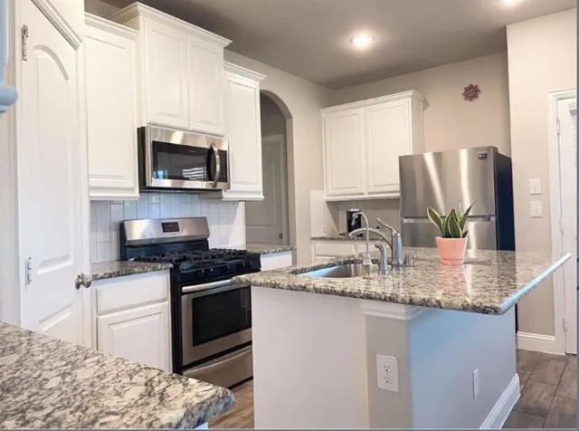 a kitchen with stainless steel appliances granite countertop a sink stove microwave and refrigerator