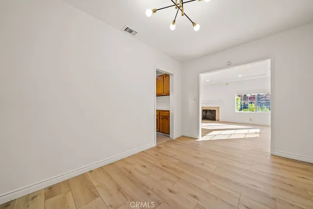 an empty room with chandelier fan and windows