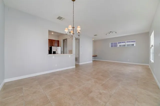 a view of a livingroom with a chandelier fan and kitchen view