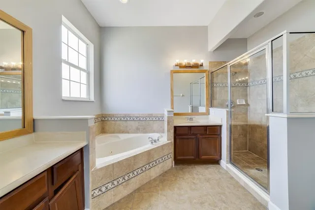 a spacious bathroom with a tub sink shower and mirror