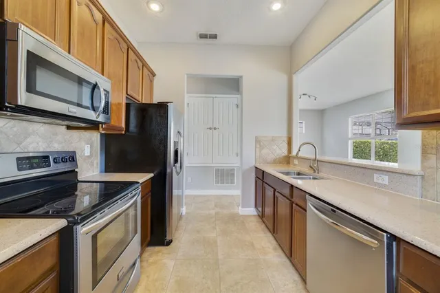 a kitchen with stainless steel appliances granite countertop a sink stove and refrigerator