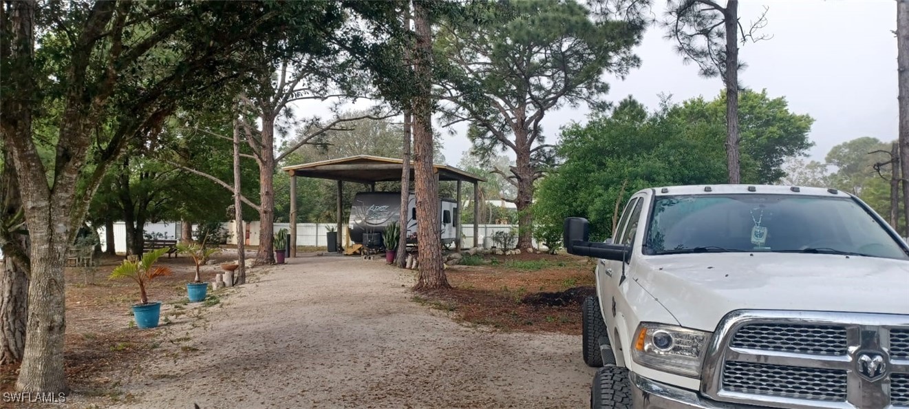 810 South Cabbage Palm Street Clewiston, FL 33440 - Photo 22 of 32 a view of a patio with table and chairs under an umbrella with large trees