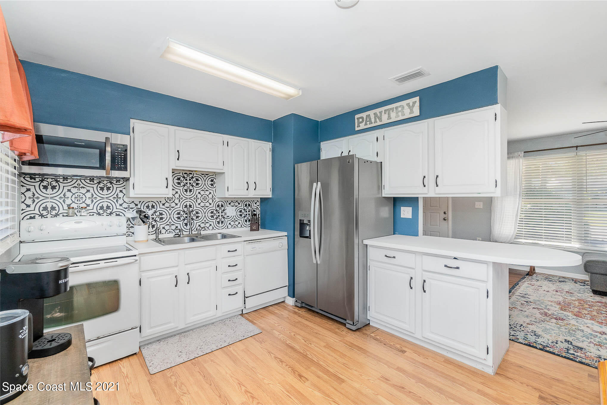 6921 Bentley Road Cocoa, FL 32927 - Photo 11 of 26 a kitchen with white cabinets and stainless steel appliances