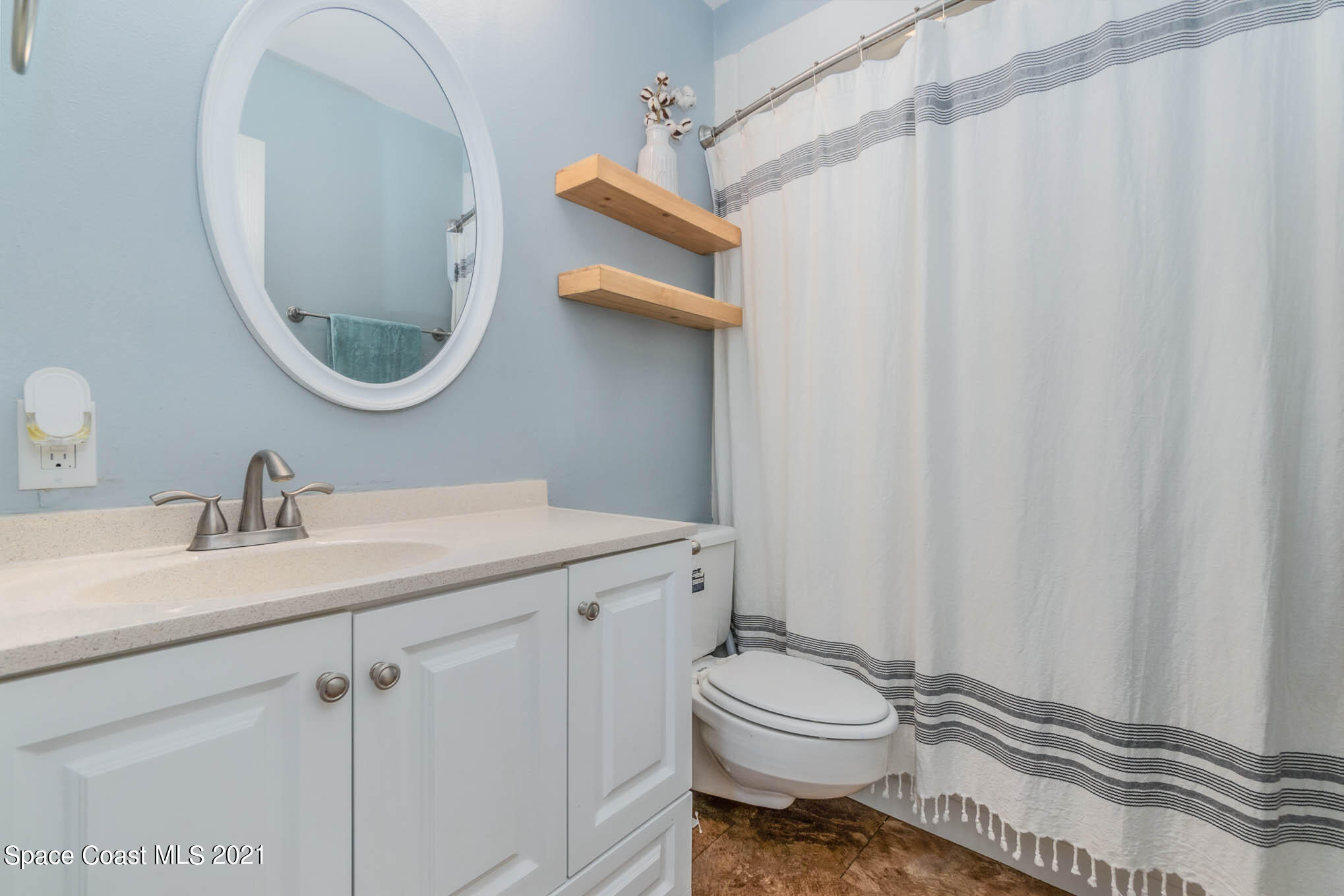 6921 Bentley Road Cocoa, FL 32927 - Photo 14 of 26 a bathroom with a sink a toilet and a mirror
