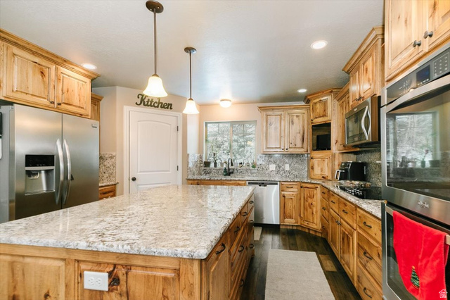 7203 East Cub River Road Preston, ID 83263 - Photo 5 of 33 Kitchen featuring stainless steel appliances, decorative backsplash, a kitchen island, and light stone counters