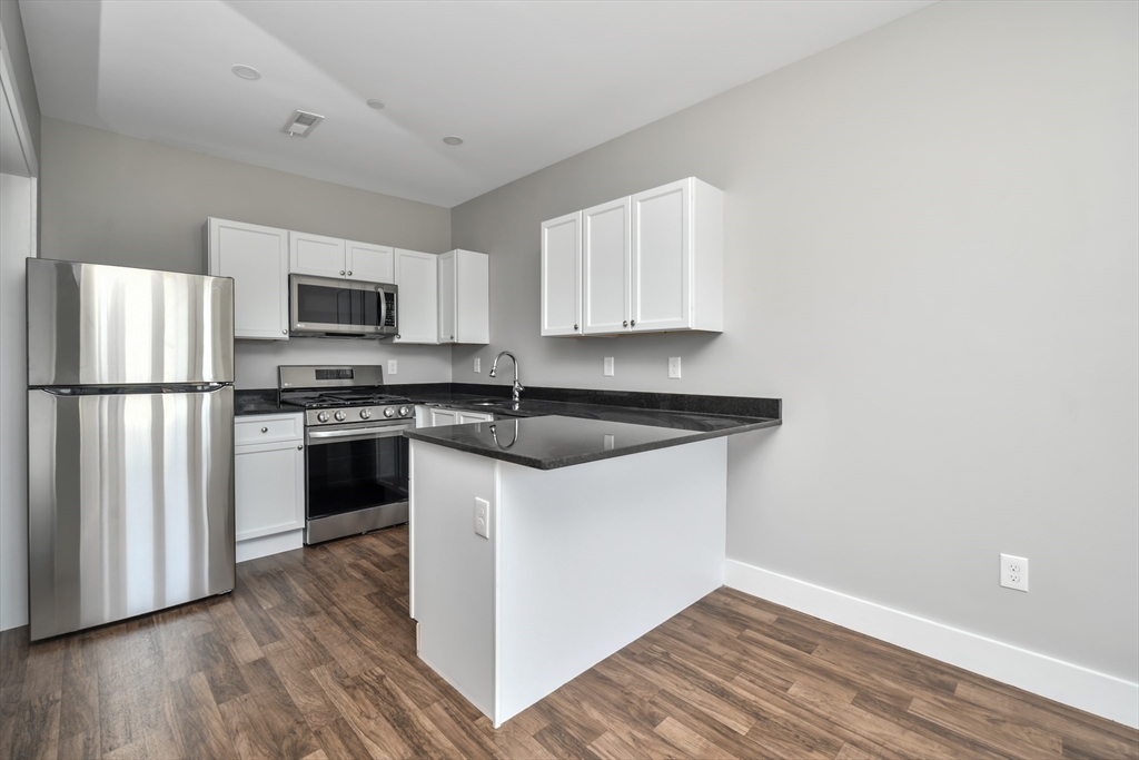 1903 Columbus Avenue Boston, MA 02119 - Photo 2 of 11 a kitchen with a refrigerator stove and wooden cabinets