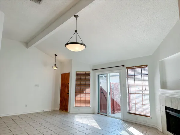 a view of an empty room with window and chandelier fan