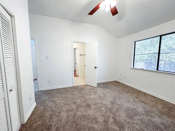 an empty room with a ceiling fan and window