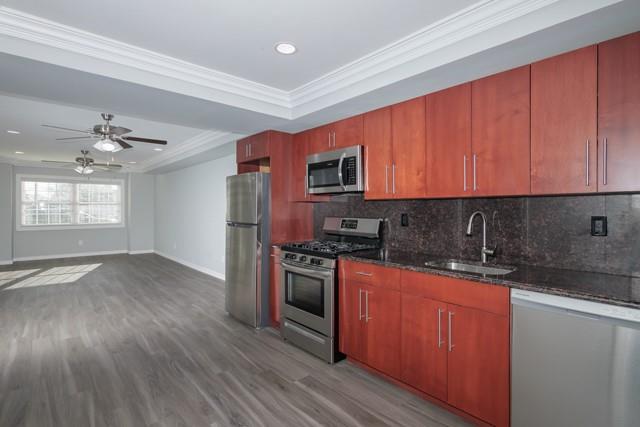 311 West Main Street, Unit 22 Patchogue, NY 11772 - Photo 4 of 9 a kitchen with stainless steel appliances granite countertop wooden cabinets a stove a sink and dishwasher with wooden floor