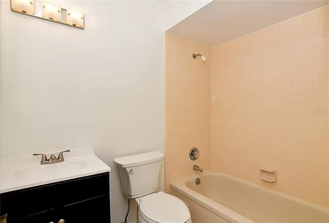 a bathroom with a bathtub shower sink vanity mirror and toilet