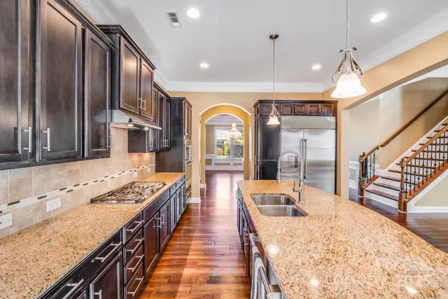 a view of a kitchen with kitchen island granite countertop a large window and stainless steel appliances