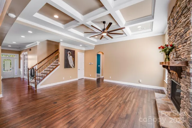 a view of an empty room with wooden floor and a ceiling fan