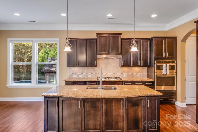 a kitchen with kitchen island granite countertop a sink and wooden cabinets