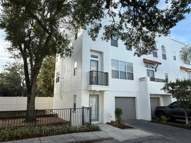 a view of a white building among the street with palm trees