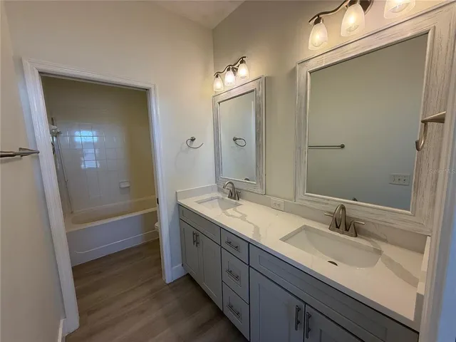 a bathroom with a double vanity sink a mirror and a bathtub