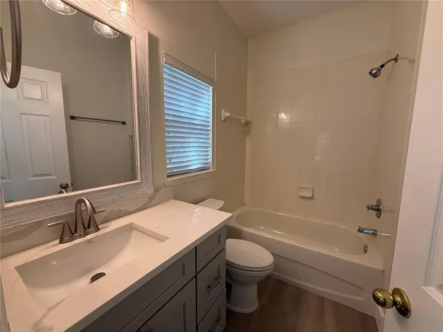 a bathroom with a sink vanity granite tub and toilet