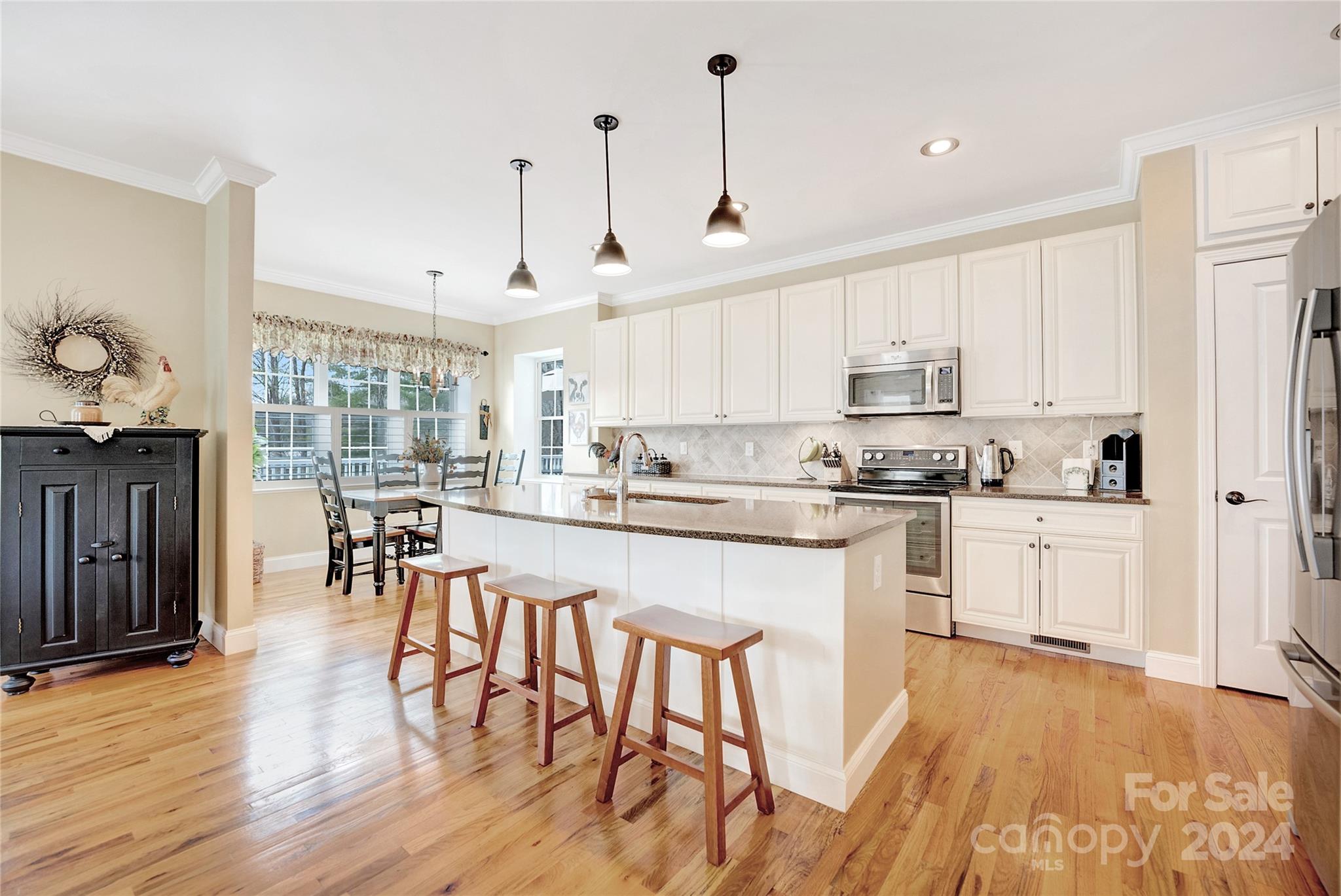 29 Willow Bend Candler, NC 28715 - Photo 15 of 45 a kitchen with stainless steel appliances granite countertop a stove a refrigerator a kitchen island a dining table and chairs with wooden floor