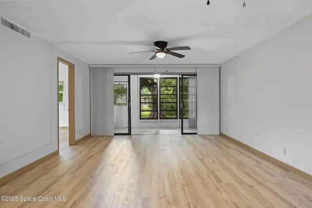 a view of an empty room with a window and wooden floor