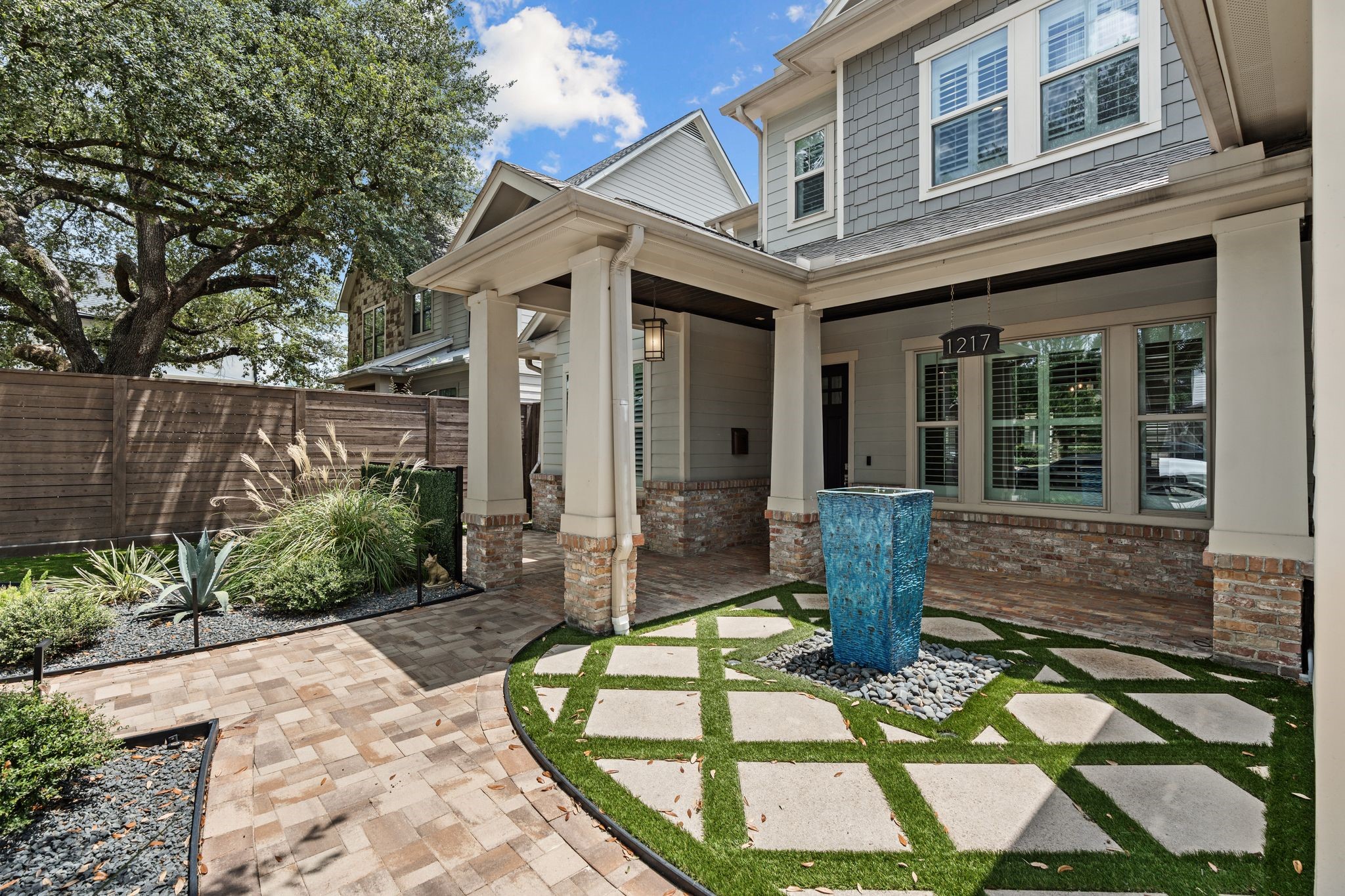 1217 Chippendale Road Houston, TX 77018 - Photo 3 of 42 Inviting covered front porch features brick flooring, bead board ceiling, & recessed lighting. A tranquil water fountain feature creates a charming outdoor moment just steps from the covered front porch.
The oversized wood front door provides a warm welcome into the home. Additional exterior improvements include a turfed side yard, automatic sprinkler system, gutters, & a new front exterior fence added in '26.