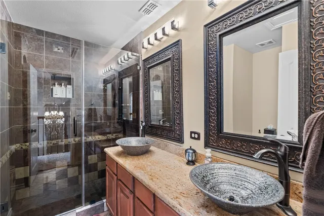 a bathroom with a granite countertop sink a mirror and shower