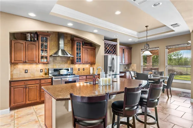a dining hall with stainless steel appliances kitchen island granite countertop a dining table and chairs