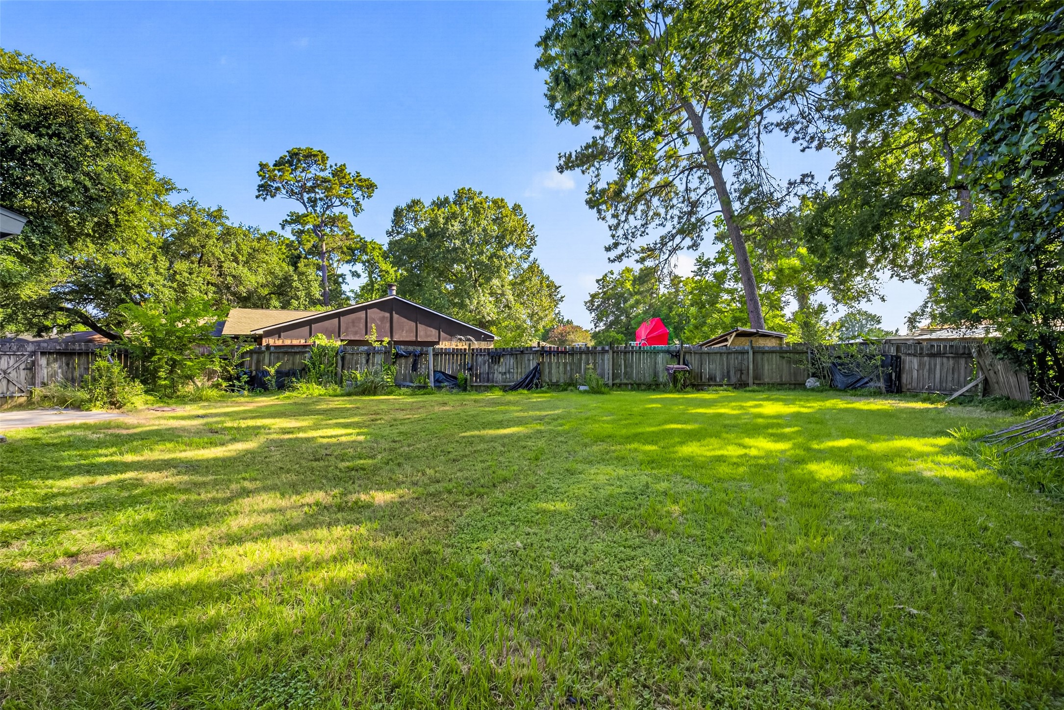 22926 Millgate Drive Spring, TX 77373 - Photo 33 of 34 Spacious backyard with lush grass, surrounded by a wooden fence and shaded by mature trees, offering a private and serene outdoor space.