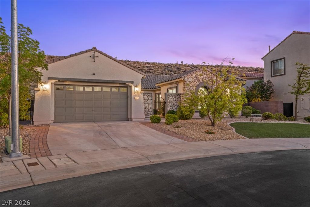 2125 De Rouge Avenue Henderson, NV 89044 - Photo 23 of 96 A desert oasis welcomes with a stone-clad facade, attached garage, and manicured landscaping.