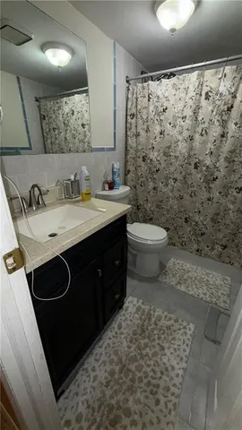 a bathroom with a granite countertop toilet sink and mirror