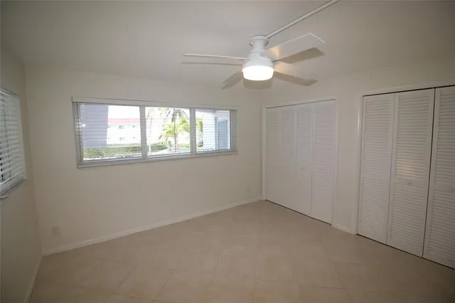 an empty room with windows and chandelier fan
