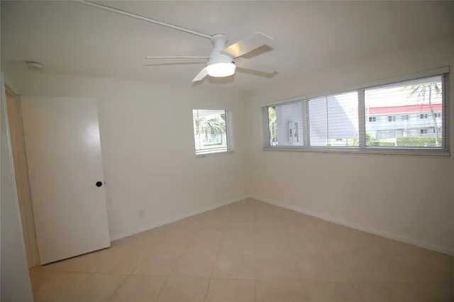 an empty room with windows and chandelier fan
