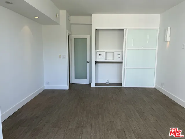 an empty room with wooden floor & closet area