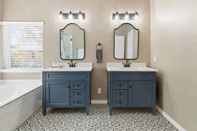 a bathroom with a double vanity sink mirror and bathtub