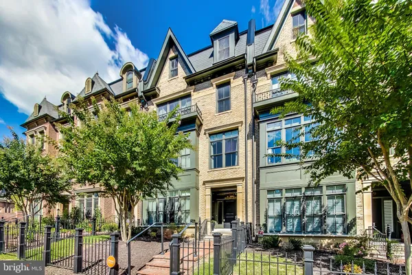 a front view of a residential apartment building with a yard and potted plants