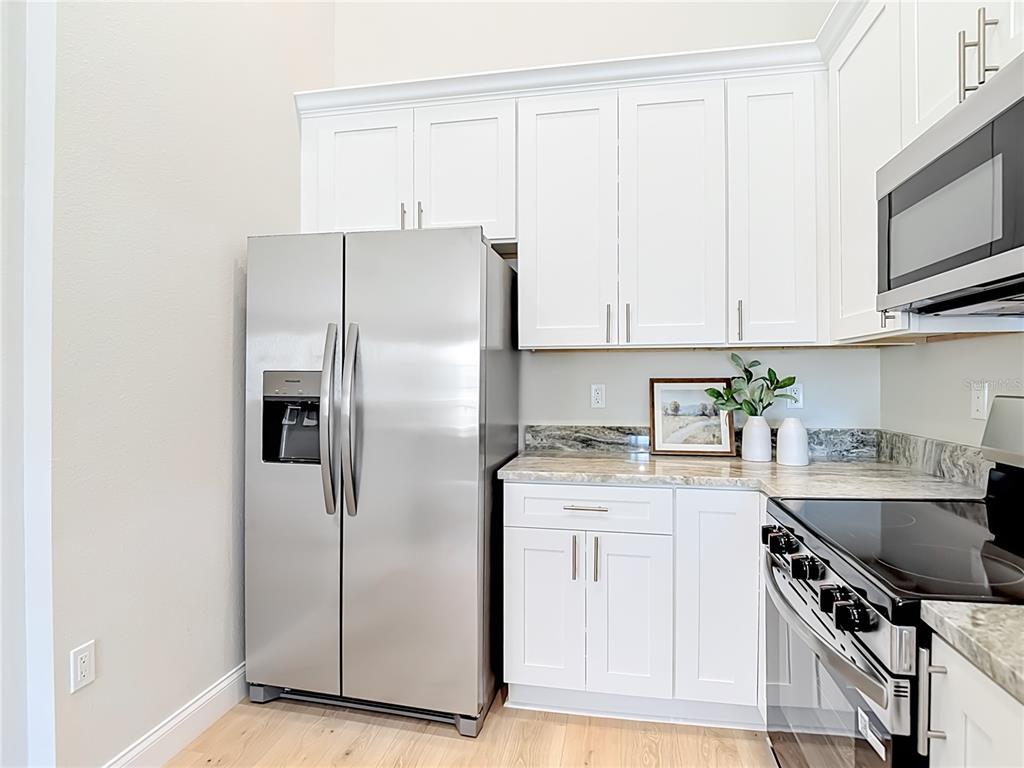 5310 Anhinga Trail New Port Richey, FL 34653 - Photo 8 of 27 a kitchen with stainless steel appliances granite countertop a refrigerator sink and white cabinets