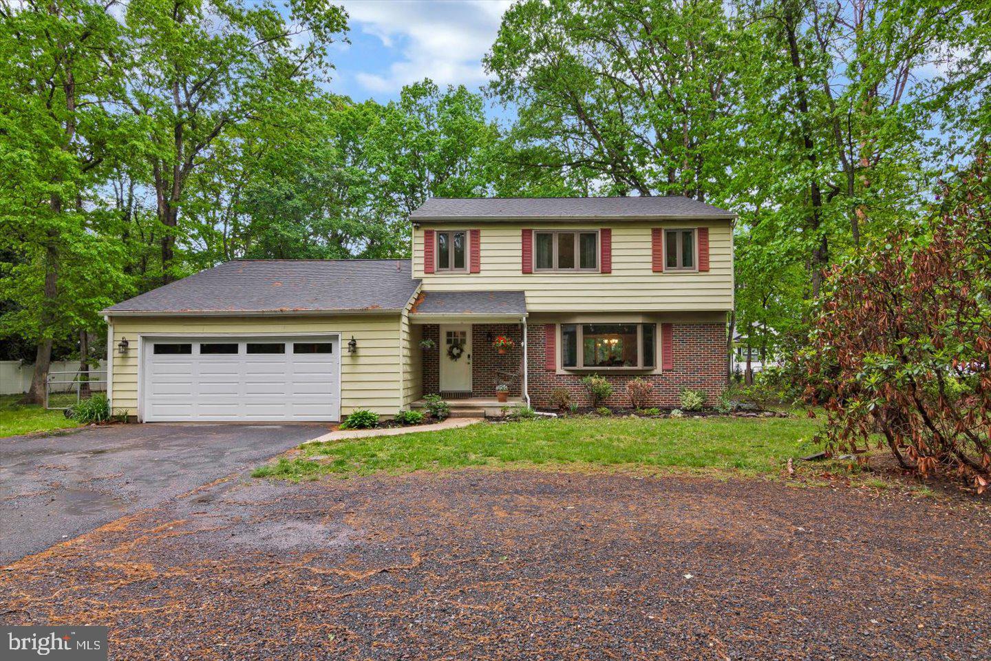 a front view of a house with a garden and trees