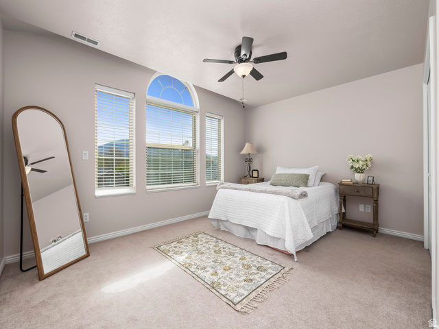 6849 North Black Powder Road Mountain Green, UT 84050 - Photo 18 of 43 Room featuring three windows with blinds, including an arched transom window, a ceiling fan with integrated lighting, and neutral-toned wall-to-wall carpeting