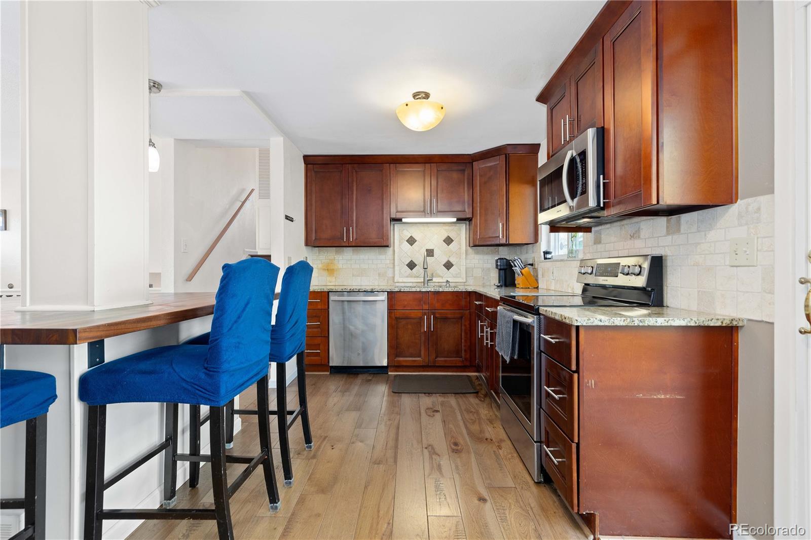 4374 East Peakview Circle Centennial, CO 80121 - Photo 13 of 45 a kitchen with stainless steel appliances granite countertop wooden cabinets a stove top oven a sink and dishwasher with wooden floor