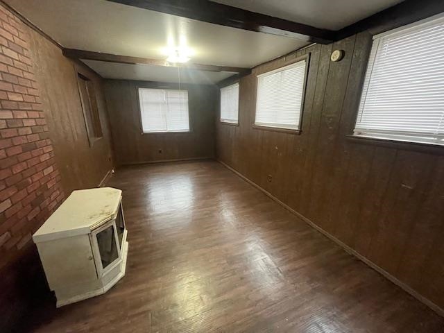 1185 Wright Road Memphis, TN 38122 - Photo 4 of 10 Empty room featuring wooden walls, beamed ceiling, dark wood-type flooring, and brick wall