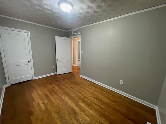 1185 Wright Road Memphis, TN 38122 - Photo 8 of 10 Unfurnished bedroom with dark wood-style flooring, ornamental molding, and a textured ceiling