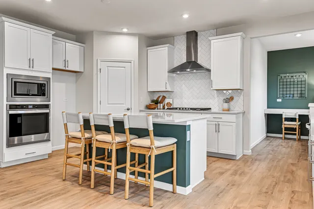a kitchen with stainless steel appliances kitchen island granite countertop a table chairs sink and cabinets